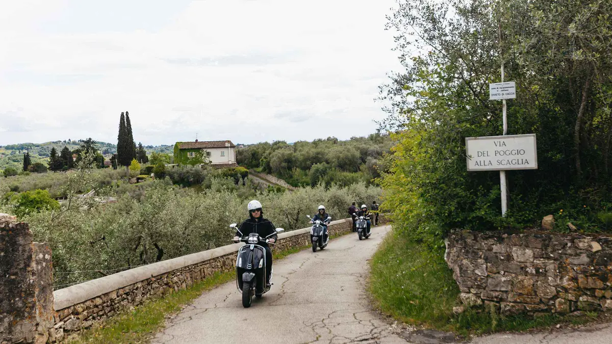 Vintage Vespa parked on a cypress-lined road on a Tuscan countryside Vespa tour